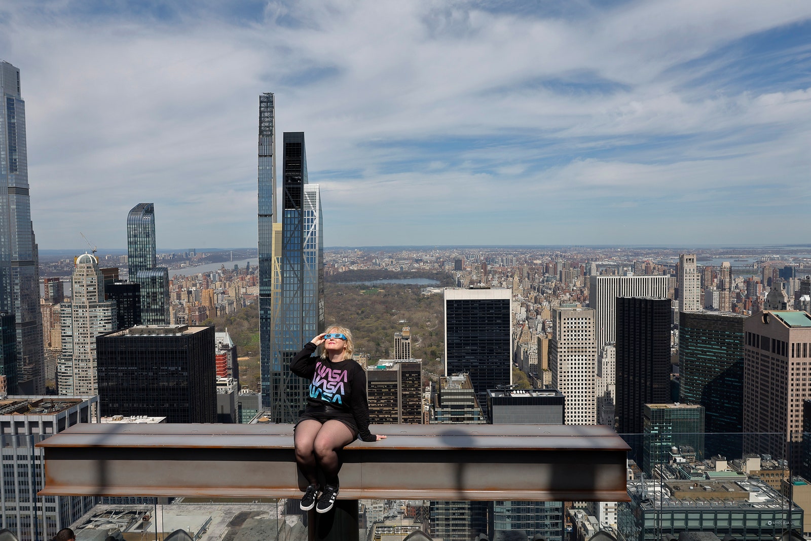 Photo of woman wearing eclipse glasses at the Beam as she prepares to watch a partial solar eclipse from the Top of the...